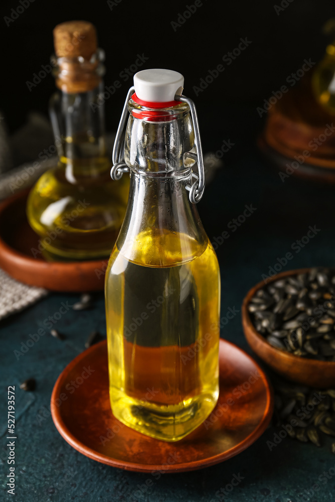 Glass bottle of sunflower oil on dark background, closeup