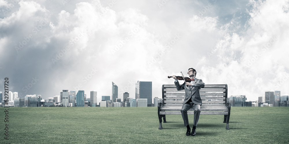 Handsome businessman in park on wooden bench play his melody