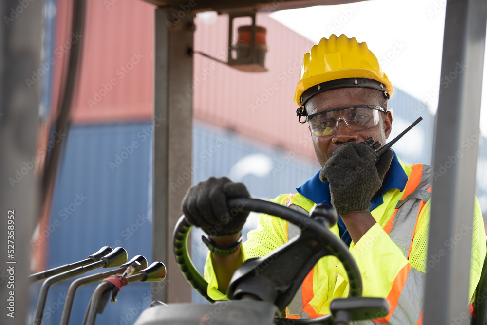 Worker man driving forklift in industrial container warehouse.
