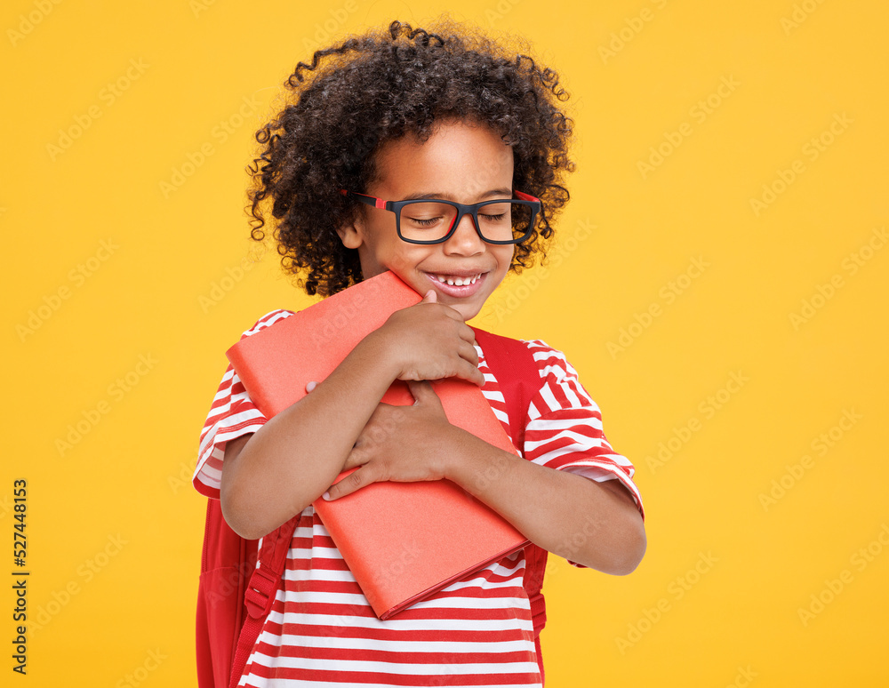 Happy ethnic schoolboy with book