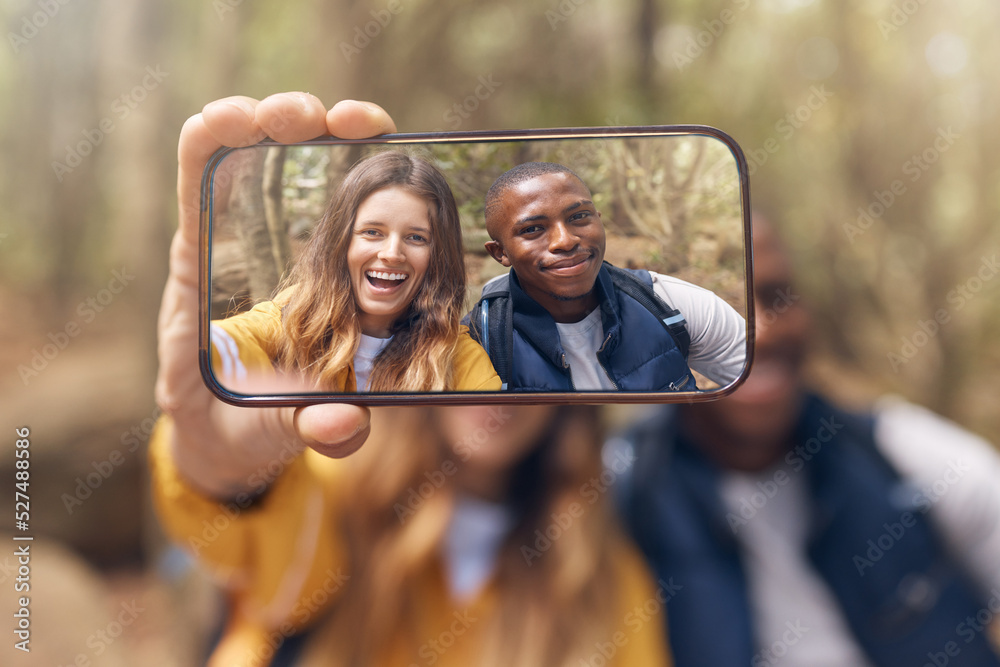 Happy couple taking a selfie on a phone while in nature on a romantic date in the forest. Multiracia