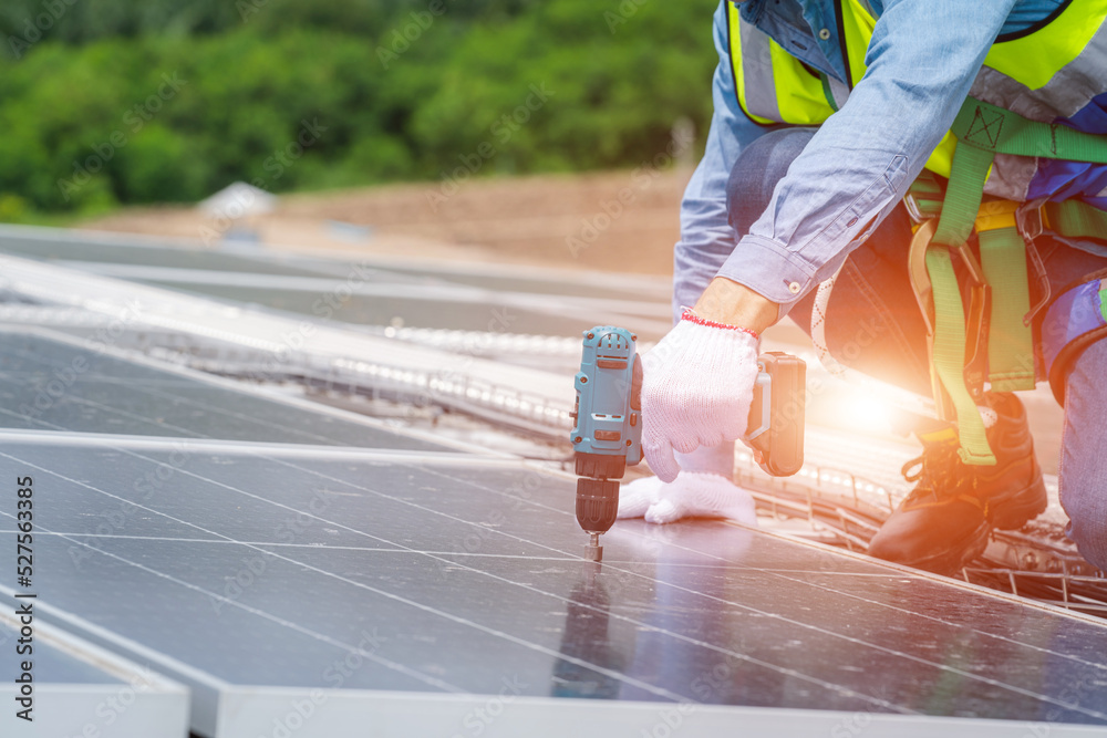 Solar panel technician with drill installing solar panels on roof factory,Sun energy,Solar panel.