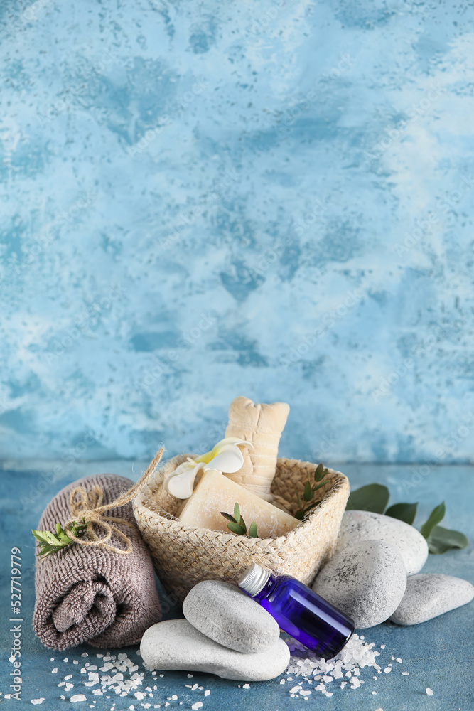 Spa composition with clean towel and stones on color background