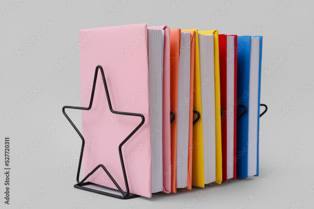 Black metal holder with books on grey background