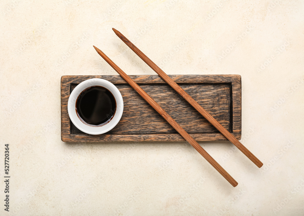 Bowl of soy sauce, chopsticks and wooden board on white background