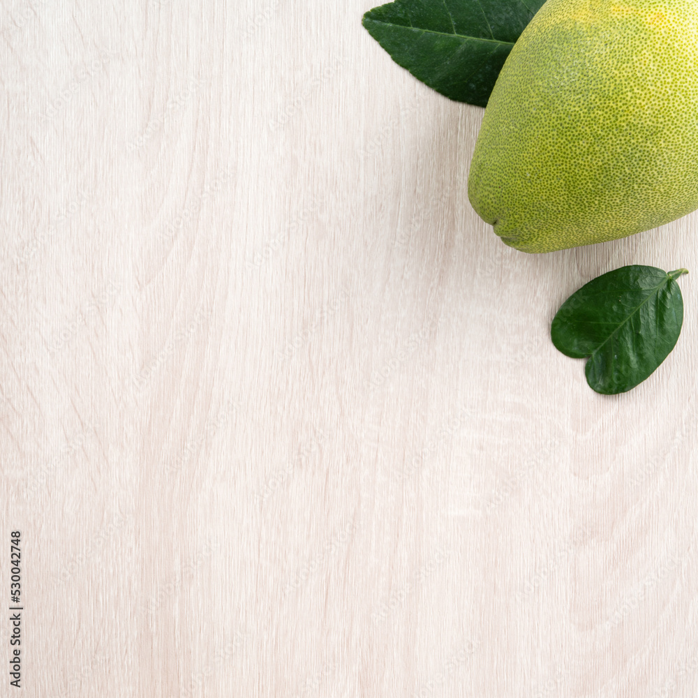 Fresh pomelo fruit on bright wooden table background.