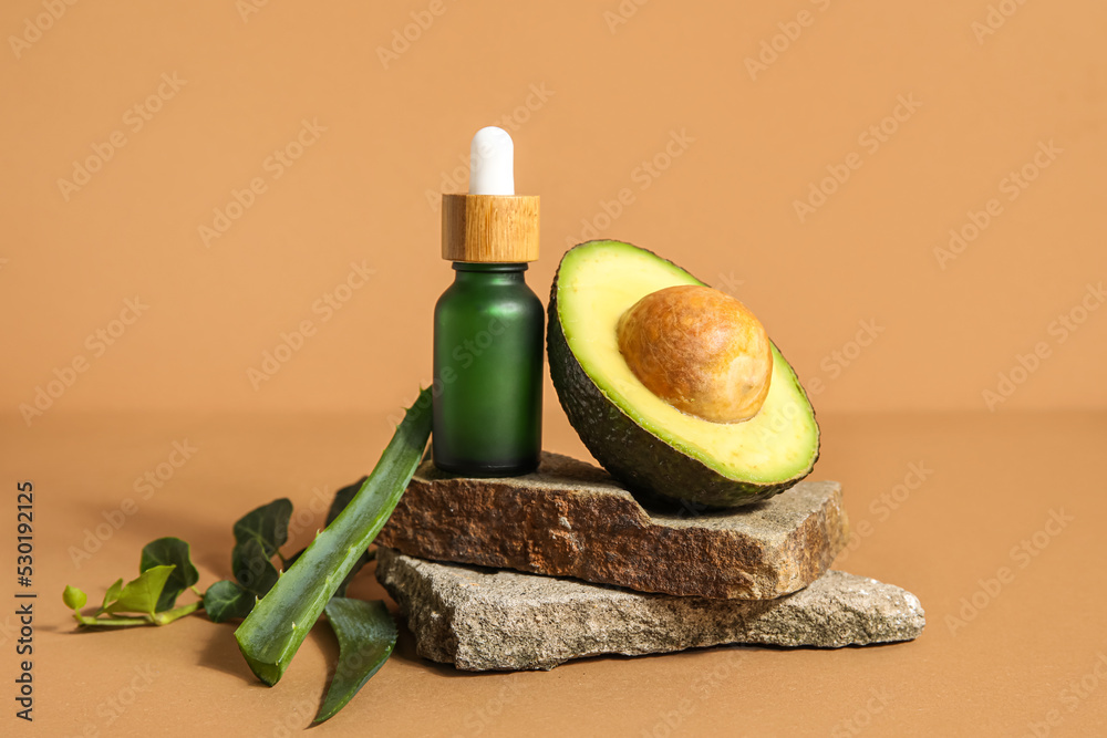 Composition with bottle of essential oil, avocado and aloe leaves on color background