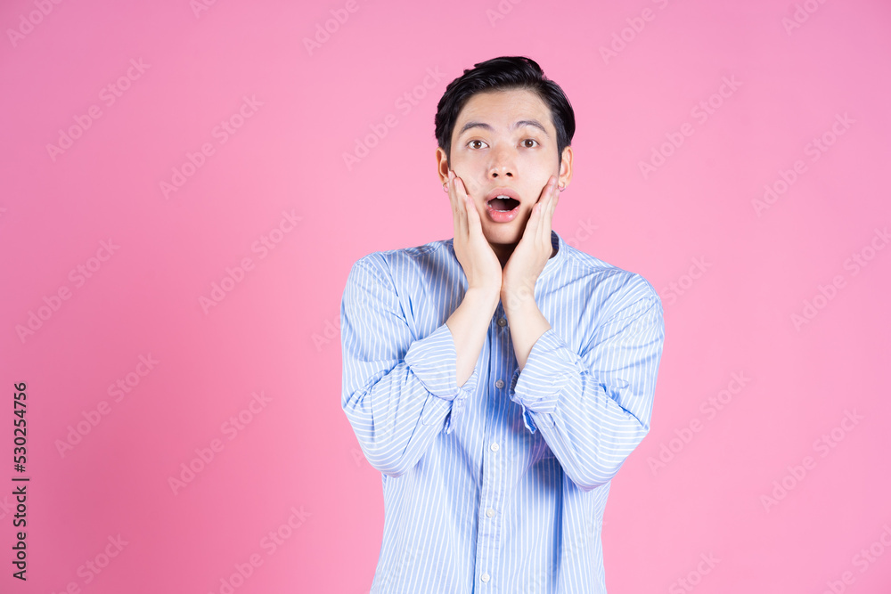 Portrait of young Asian man on pink background