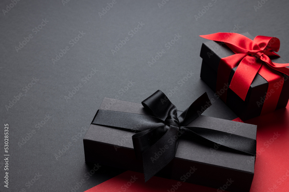 Composition of presents with pink and black ribbons on gray and pink background