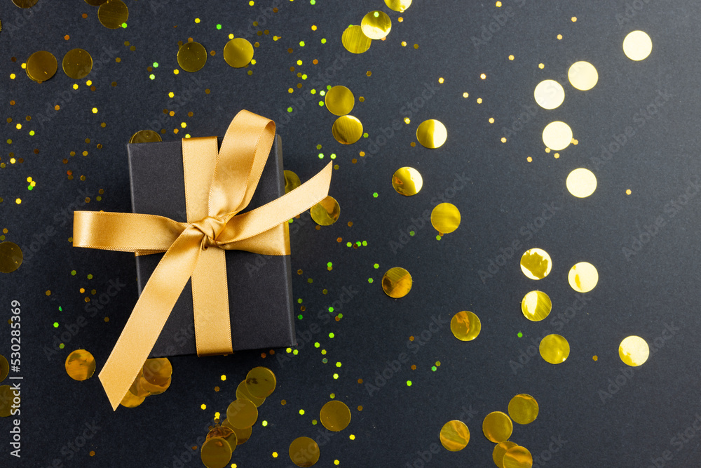 Composition of present with gold ribbon and spots on gray background