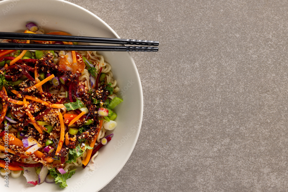 Overhead view of asian wok stir fry and chopsticks with copy space on grey background