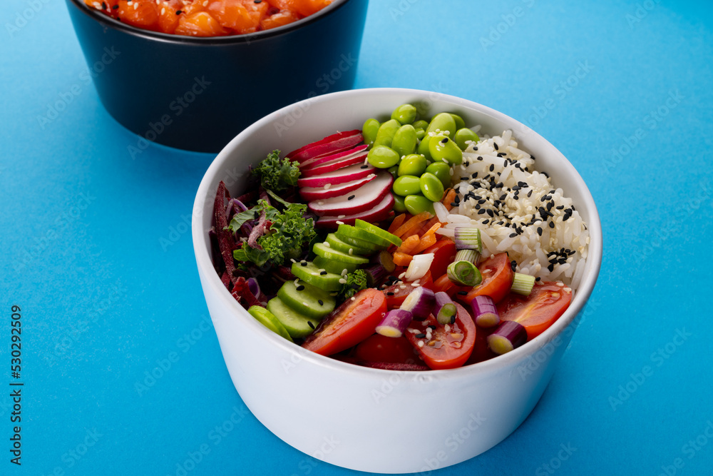 Overhead view of two hawaiian poke bowls on blue background