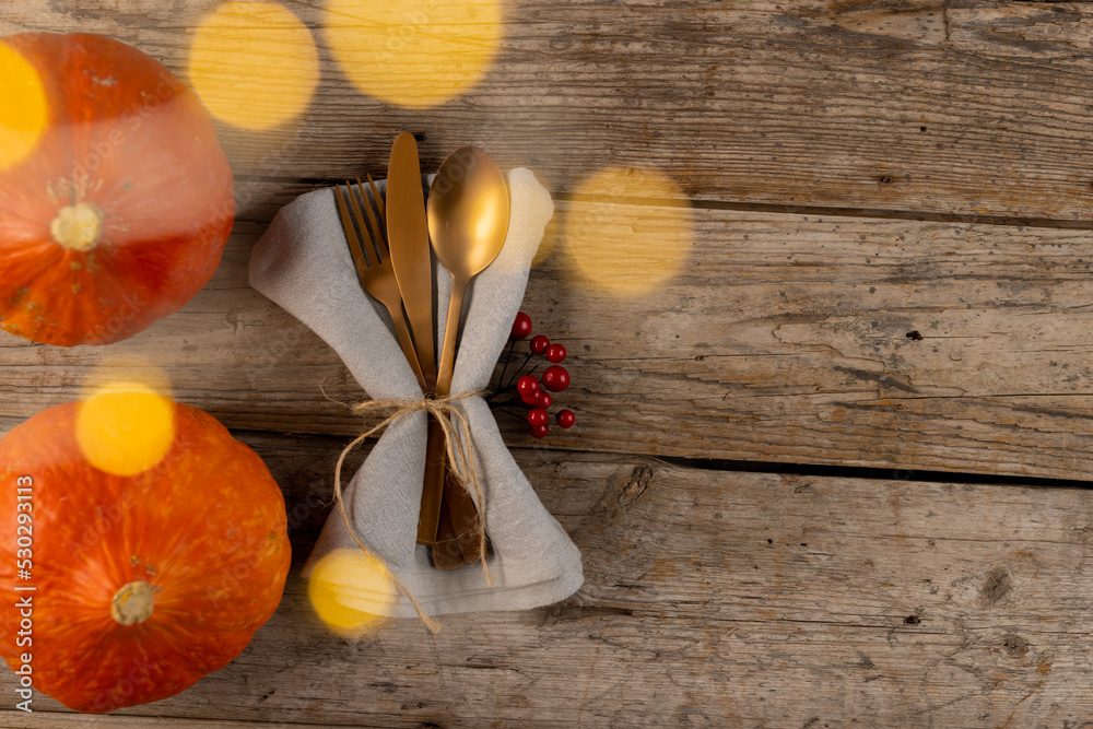 Overhead view of cutlery in napkin with autumn decoration and copy space on wooden background