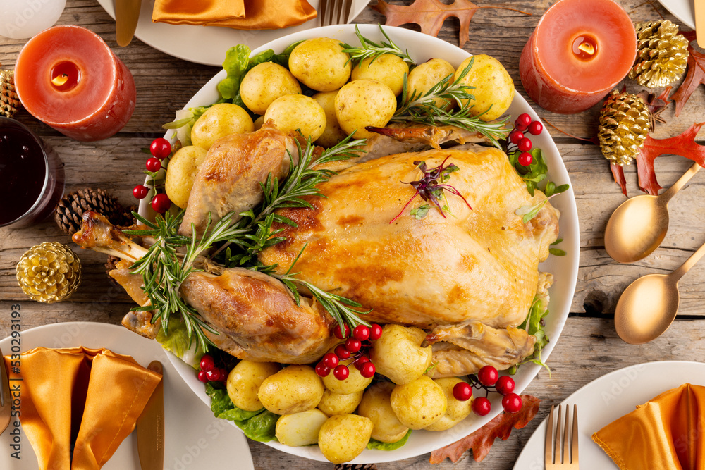 Overhead view of thanksgiving table with roast turkey, potatoes, candles and autumn decoration