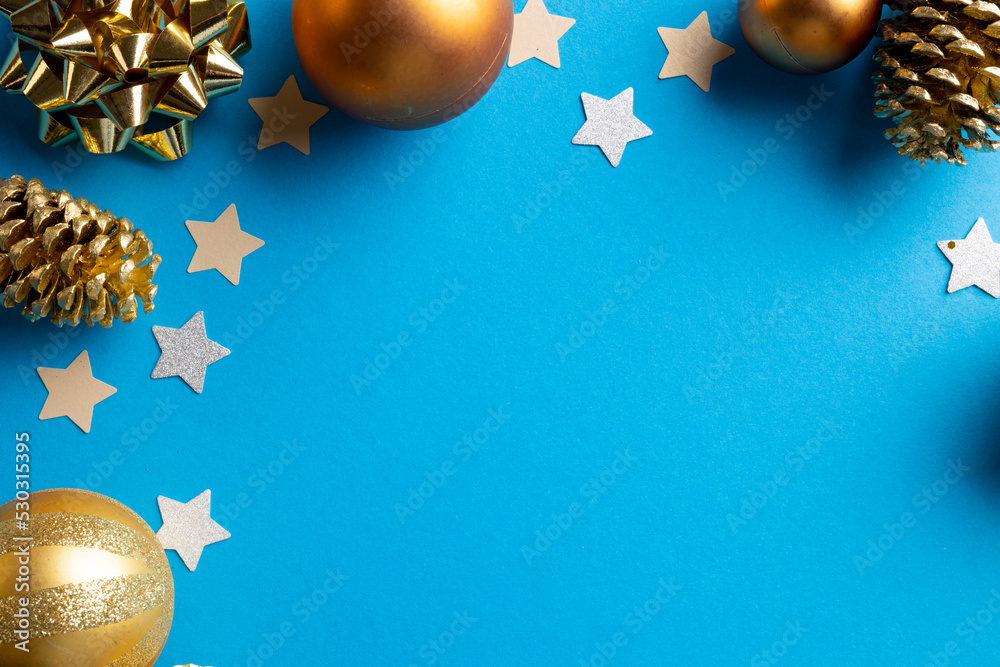 Image of christmas decoration with baubles and stars and copy space on blue background