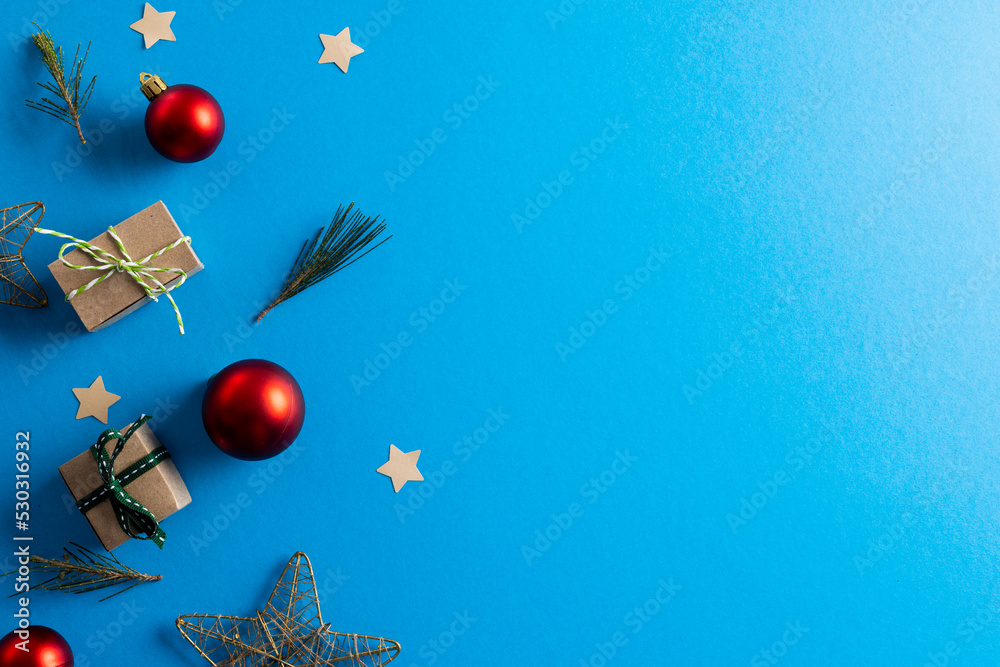 Image of christmas decoration with gifts, baubles and copy space on blue background