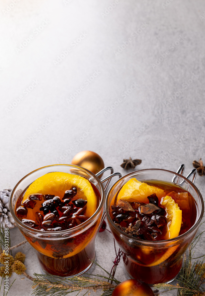 Image of two cups of tea with spices and lemon and christmas decorations with copy space on grey