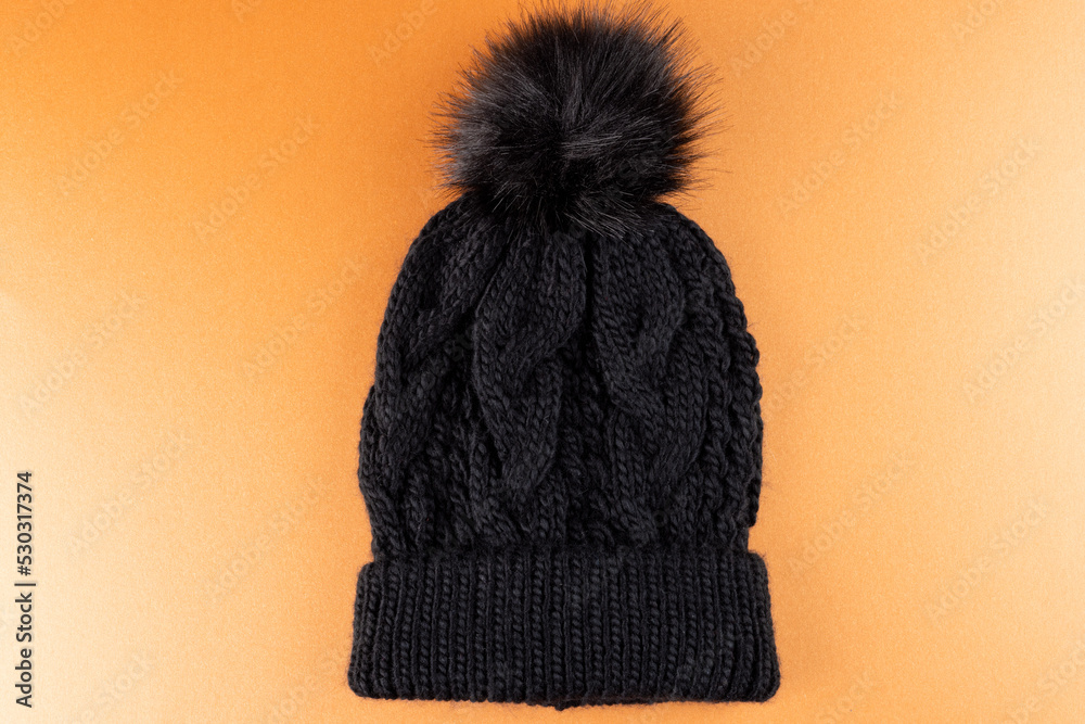 Image of wool beanie with pom pom on yellow surface