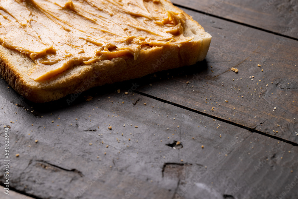 Image of bread slice with peanut butter on wooden surface