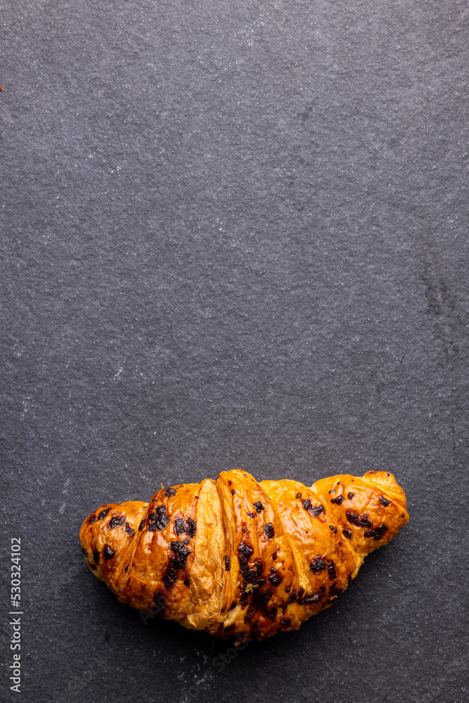 Vertical image of croissants lying on wooden board on dark grey surface