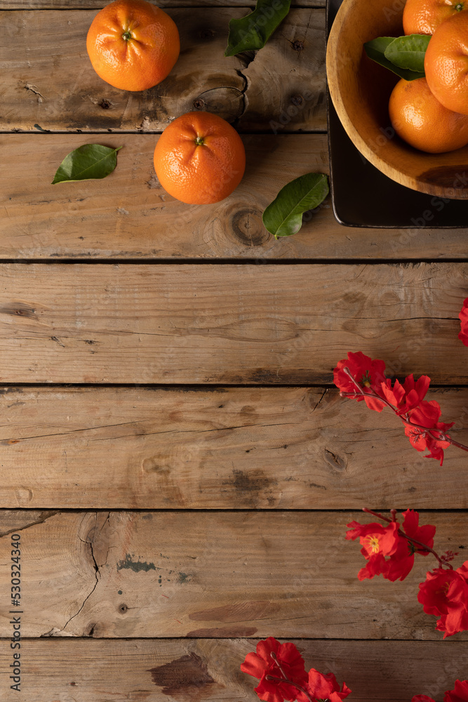 Composition of red flowers and oranges on wooden background