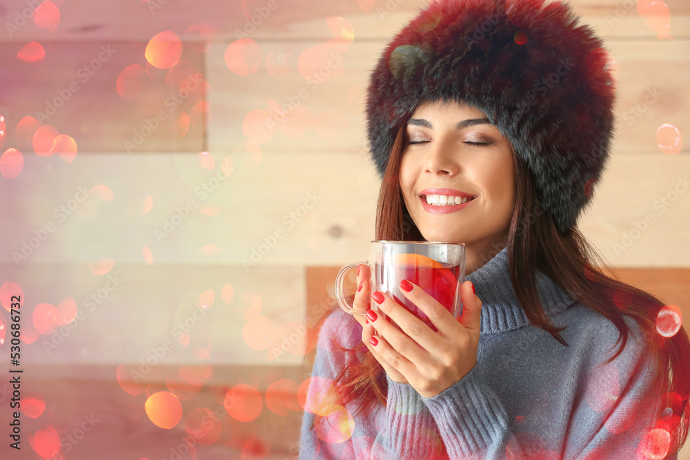 Woman with glass cup of delicious mulled wine on wooden background