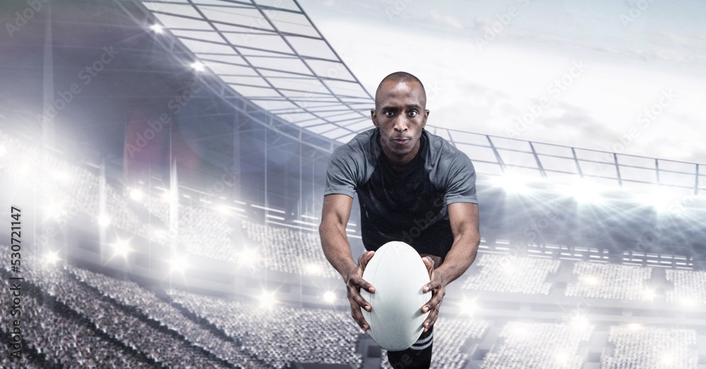 Composition of male rugby player holding rugby ball over sports stadium