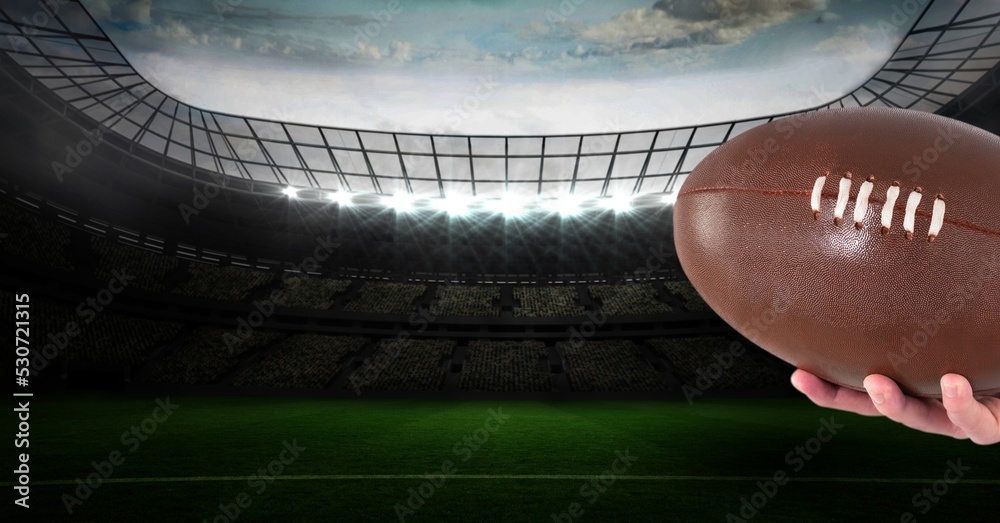 Composition of male rugby player holding rugby ball over sports stadium