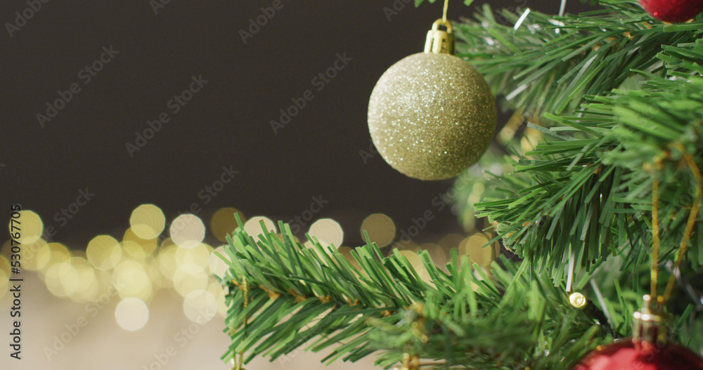 Image of christmas tree with baubles and fairy lights on black background