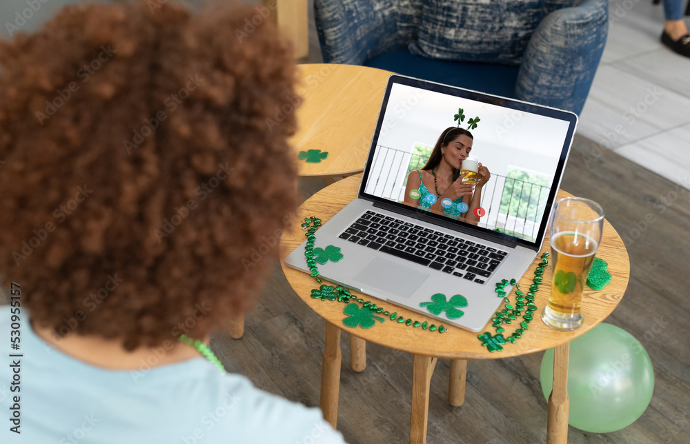 Mixed race man at bar making st patricks day video call to female friend on laptop