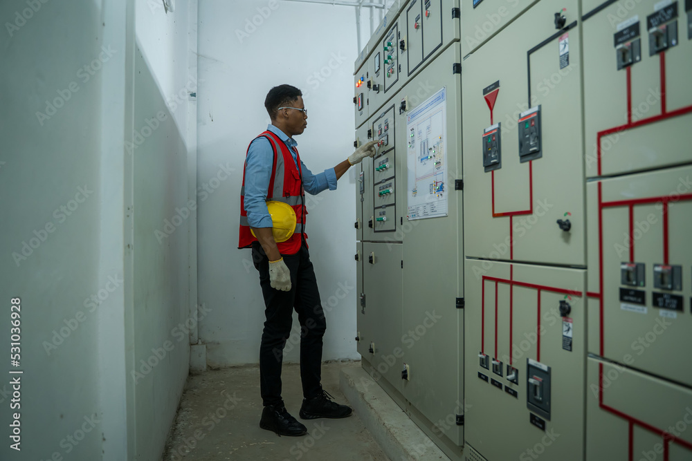 Engineer working in electrical room with power energy motor machinery cabinets with panel in control