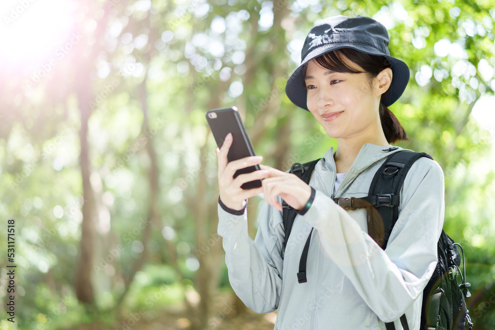 山でスマートフォンを使う女性