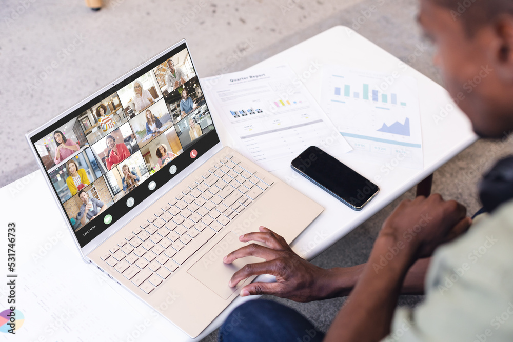 Businessman with documents and phone on desk discussing with multiracial coworkers on video call