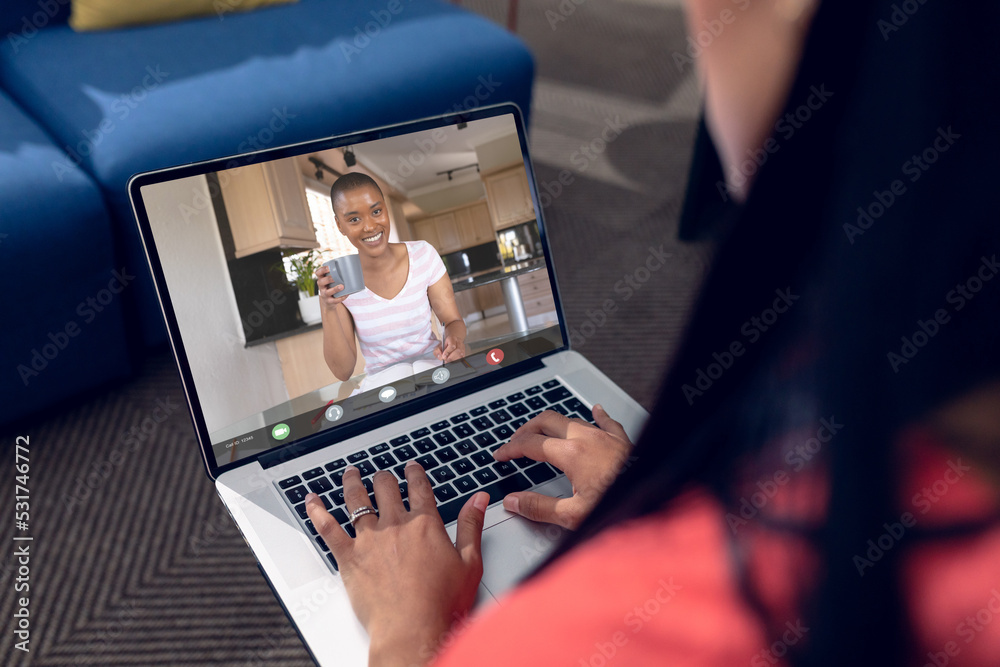 Multiracial female coworkers talking on video conference over laptop at home