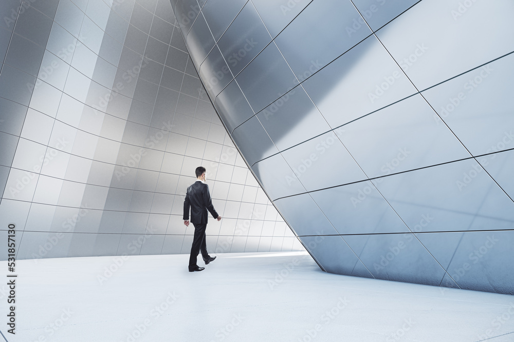 Businessman walking in abstract glass building open space interior.