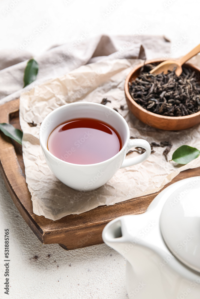 Composition with dry tea leaves and cup of hot beverage on white background