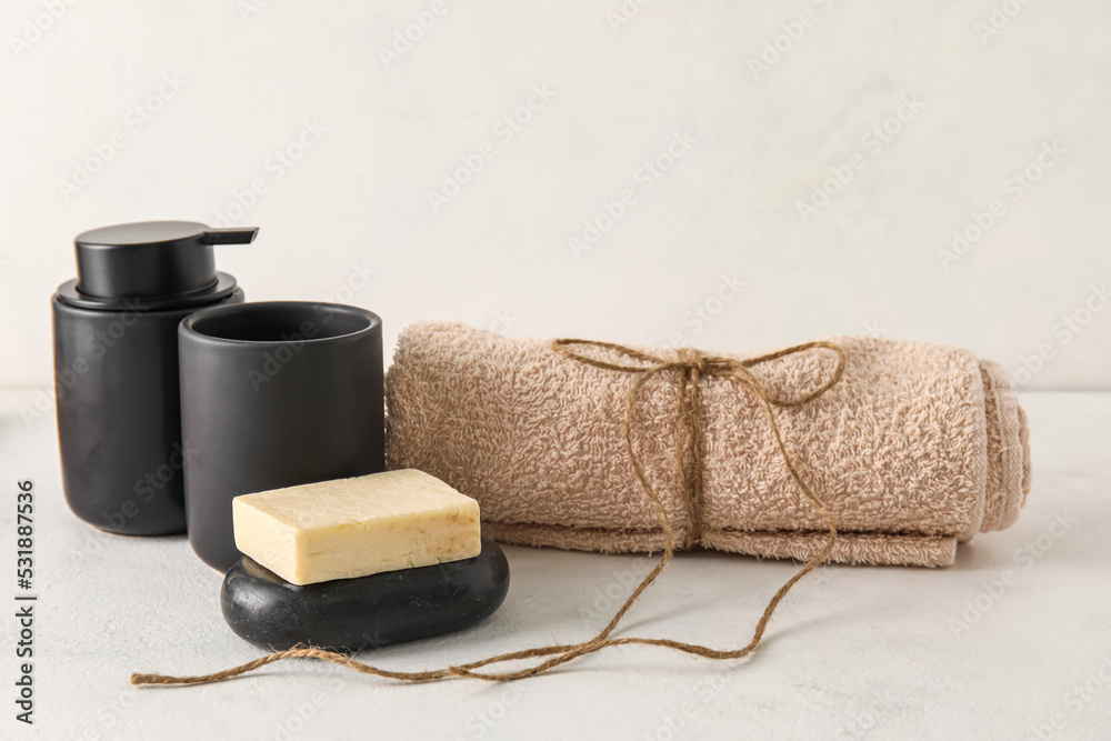 Set of bath supplies with towel on light background