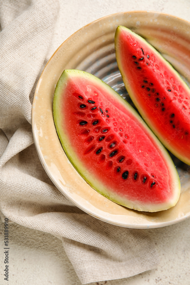 Plate with slices of watermelon and napkin on white table