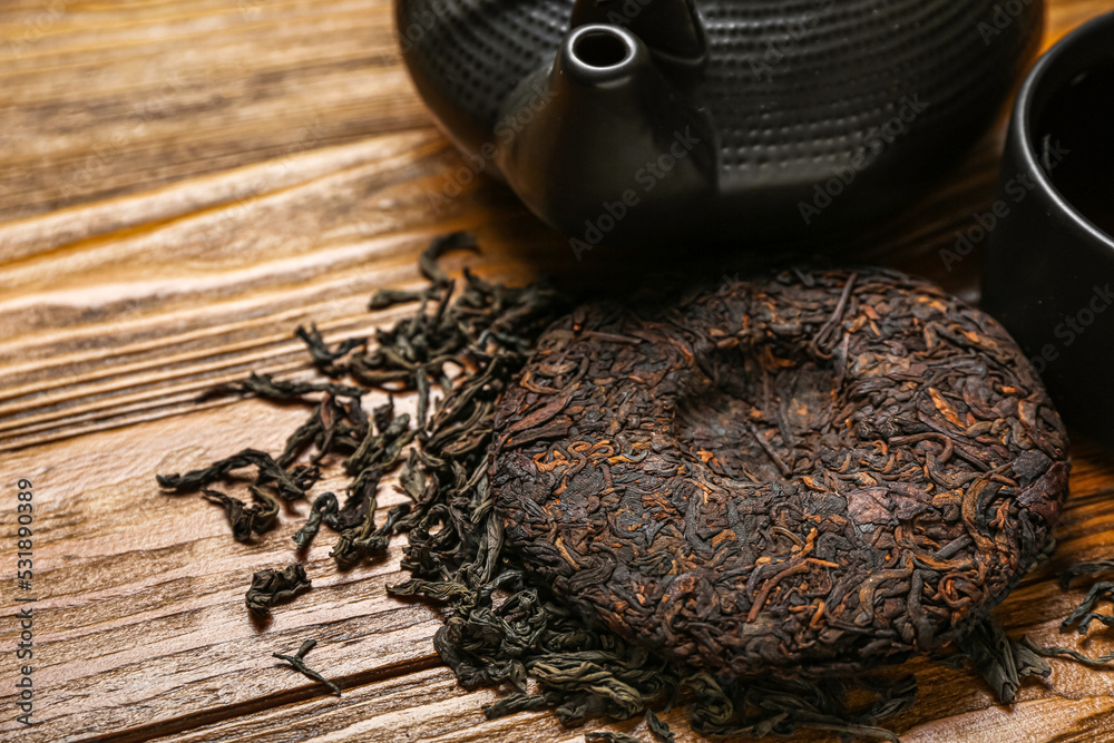 Dry pressed puer tea on wooden background, closeup