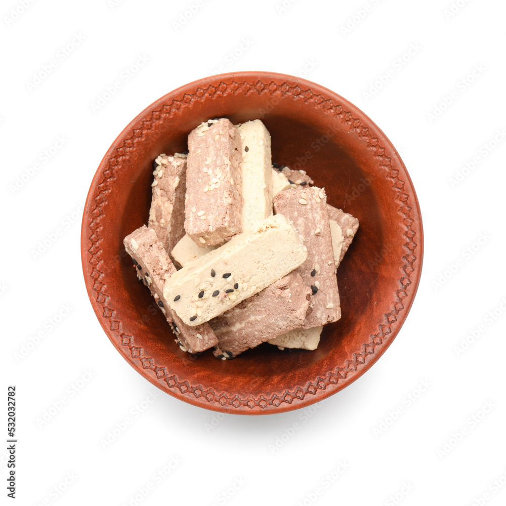 Bowl with pieces of sweet sesame halva on white background