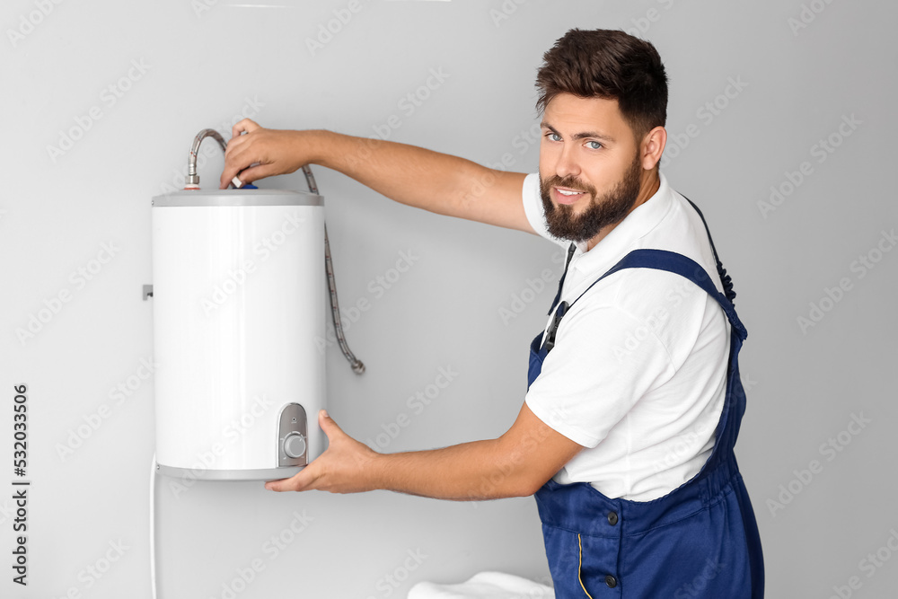 Male plumber installing boiler in bathroom