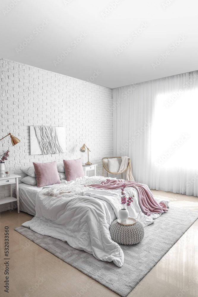 Interior of light bedroom with tables, lamps and eucalyptus branches in vases