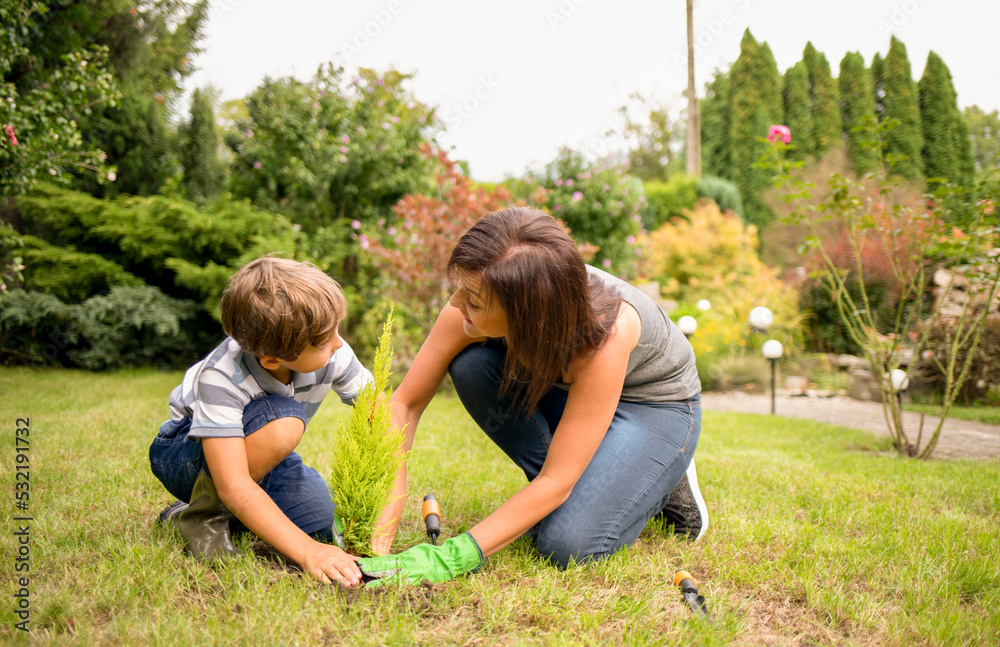 Mom and son planting plant together in garden