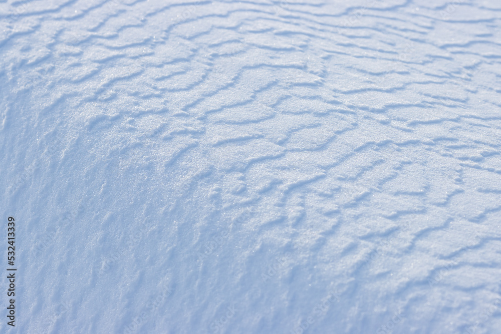 美丽的冬季背景，雪地。自然的雪纹理。风在雪上雕刻图案