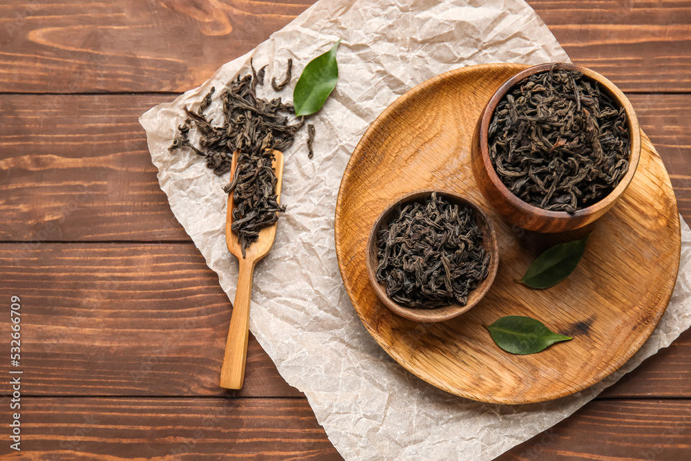 Composition with dry tea leaves on wooden background, top view