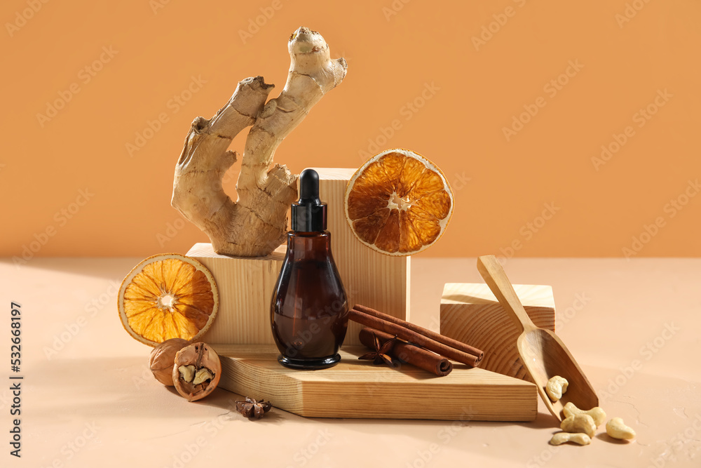 Composition with bottle of essential oil, nuts, spices and ginger root on color background