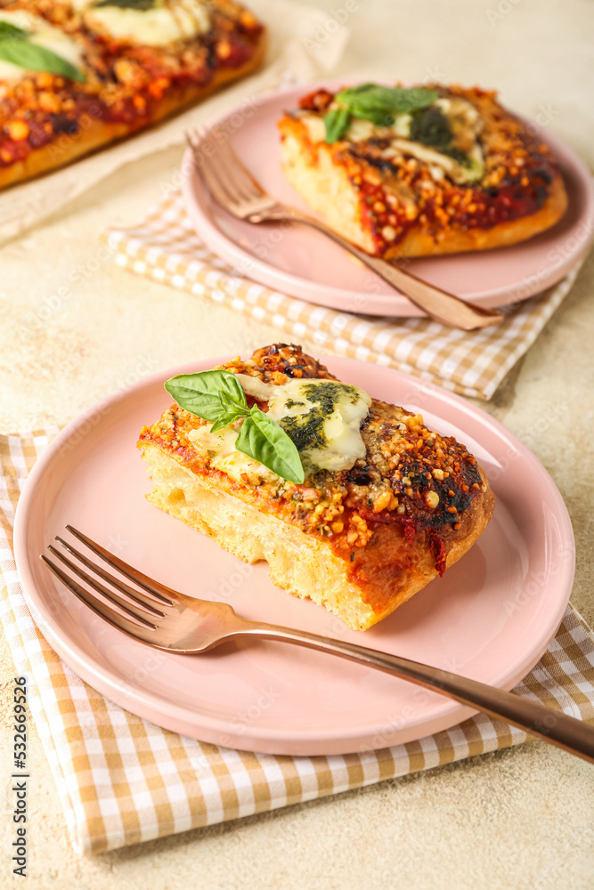 Plates of tasty Italian pie with mozzarella and pesto sauce on light table