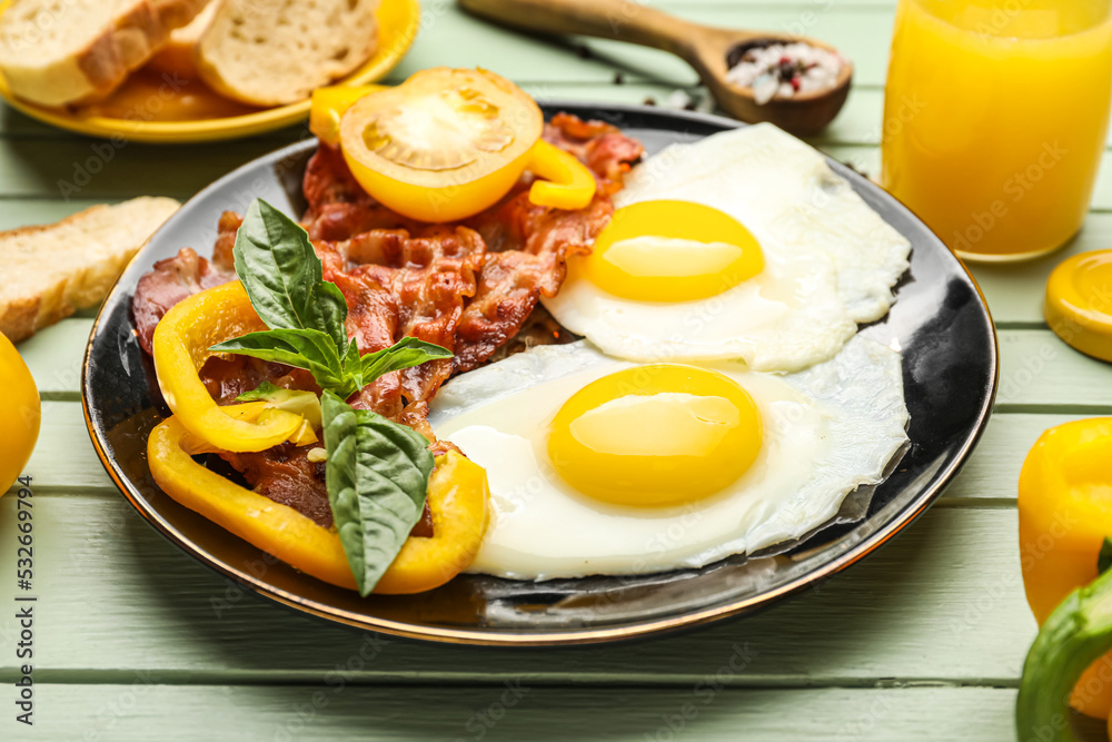 Plate with tasty fried eggs and bacon on color wooden background, closeup