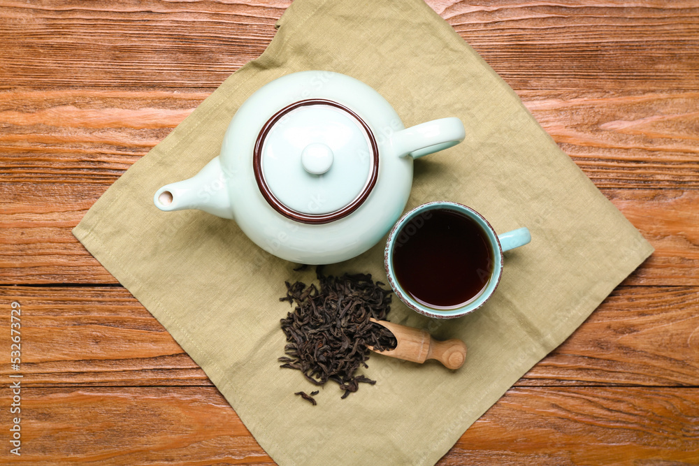 木质背景的餐巾，配有一勺干普洱茶、杯子和茶壶