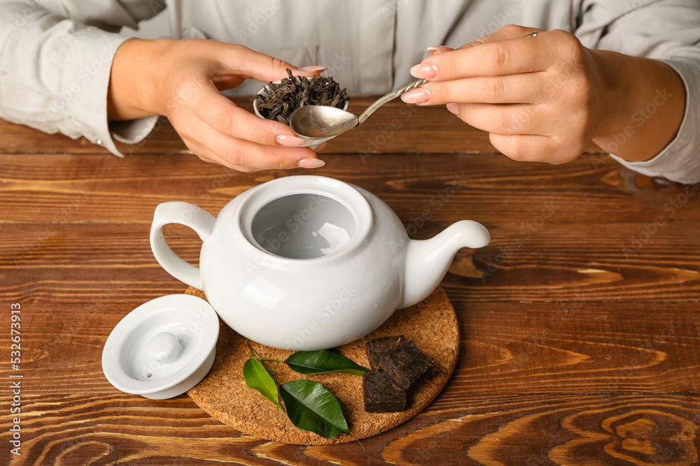 女人在木桌上冲泡普洱茶